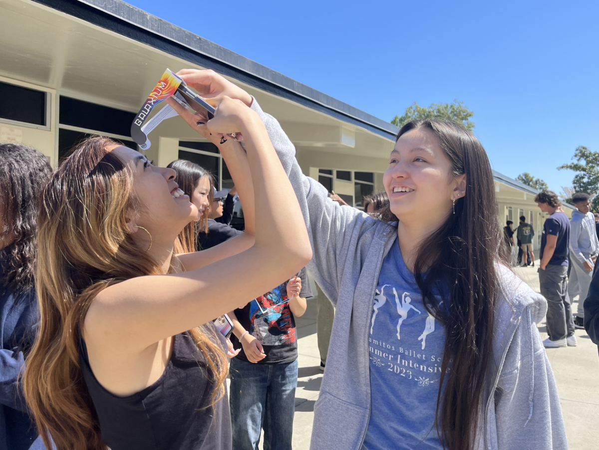 Junior Naomi Coulter (right) holds onto junior Elaine Nguyen’s solar viewer as she takes a picture of the partial solar eclipse passing by Fullerton during their second period Advanced Placement [AP] Chemistry class outside Room 115 on Monday, April 8. Chemistry teacher Andrew Colomac, along with the other science teachers in the 110s wing, allowed his students to view the eclipse at its peak with the glasses he provided.